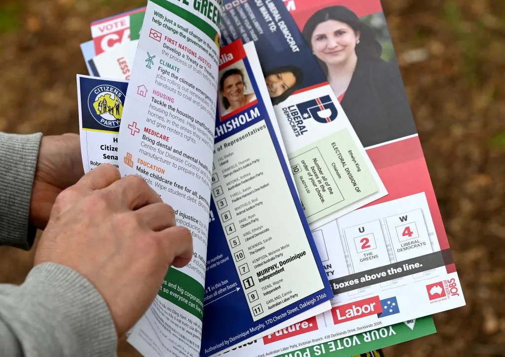 A man holds political party pamphlets as voters queue at a pre-polling centre in the seat of Chisholm in Melbourne, Australia, on May 19, 2022. (William West/AFP via Getty Images)