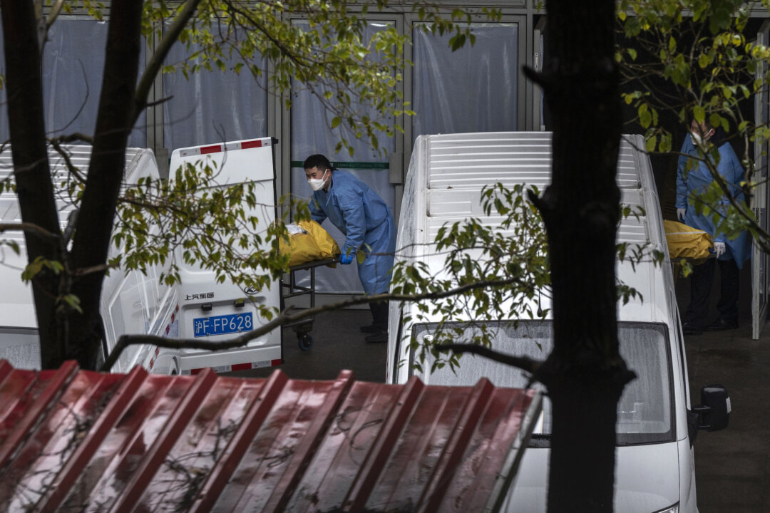 Funeral workers load bodies into vans to be taken for cremation at a busy local funeral home in Shanghai on Jan. 13, 2023. (Kevin Frayer/Getty Images)
