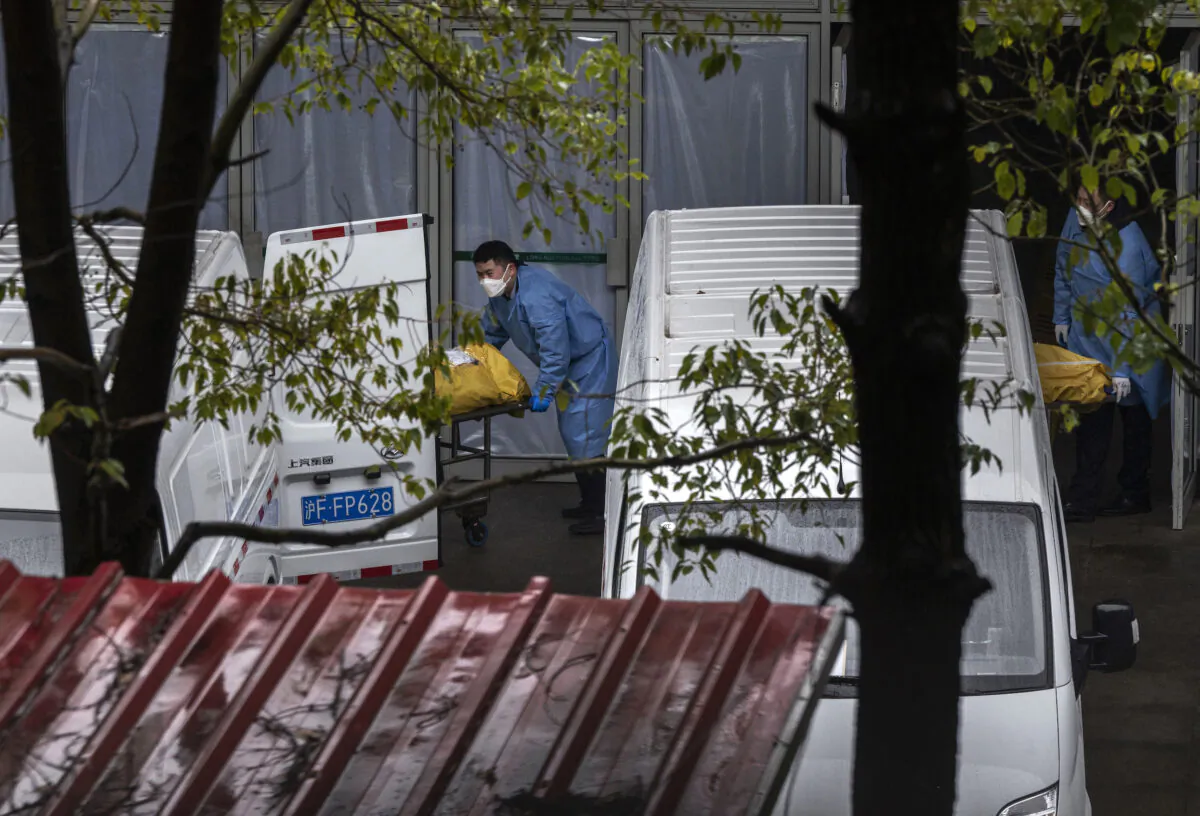 Funeral workers load bodies into vans to be taken for cremation at a busy local funeral home in Shanghai on Jan. 13, 2023. (Kevin Frayer/Getty Images)