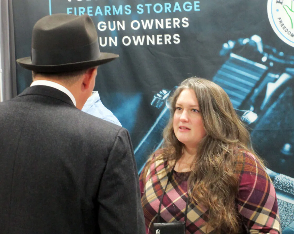 Sarah Joy Albrecht, founder and executive director of Hold My Guns, talks with a visitor to her organization's booth at the National Shooting Sports Foundation's 45th annual SHOT Show in Las Vegas, Nevada, on Jan. 18, 2023. (Michael Clements/The Epoch Times)