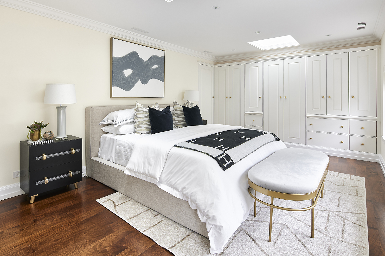 A decorative bench provides a glamorous touch at the foot of a bed in a primary bedroom. 