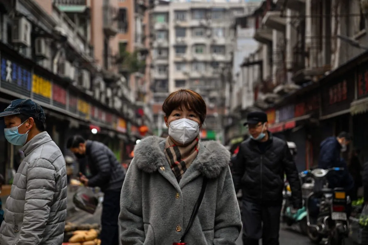 People walk down a street next to a local market in Wuhan, in China's central Hubei Province, on Jan. 23, 2023. (Hector Retamal/AFP via Getty Images)