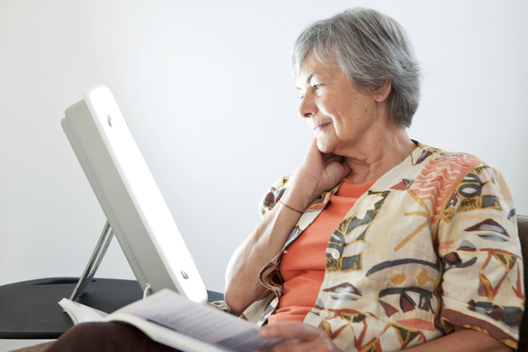 Elderly person using a light box as a form of light therapy. (Image Point Fr/Shutterstock)