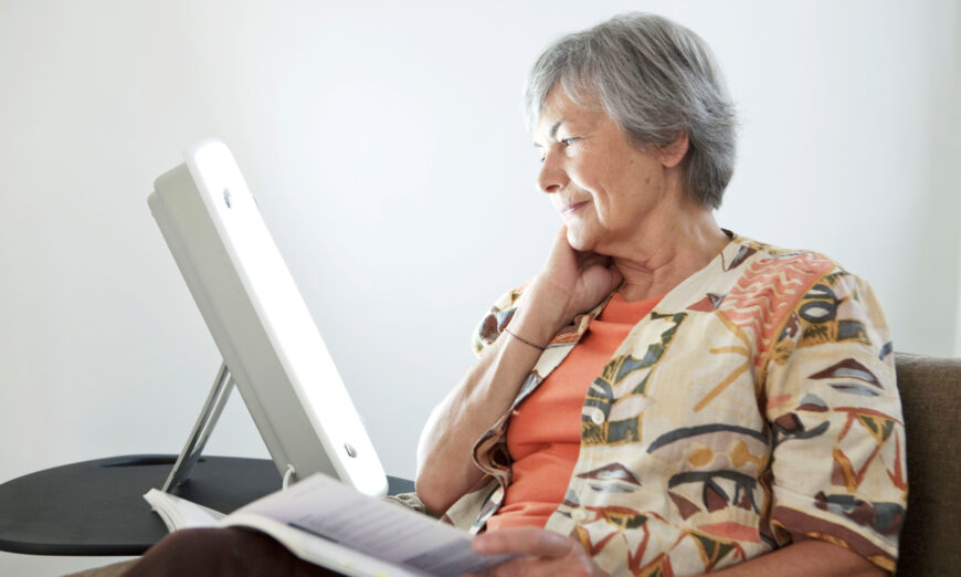 Elderly person using a light box as a form of light therapy. (Image Point Fr/Shutterstock)