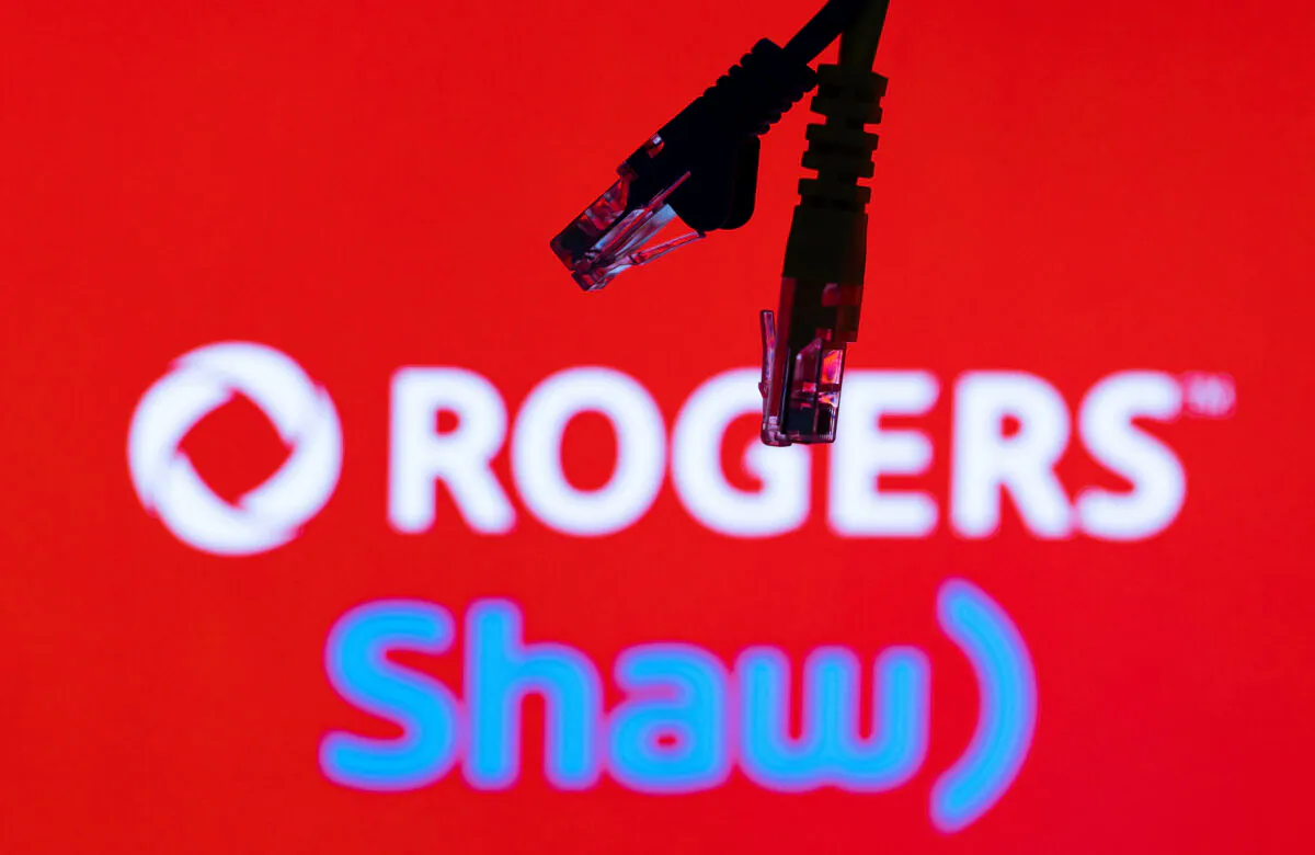 Ethernet cables are seen in front of Rogers and Shaw Communications logos on July 8, 2022. (Dado Ruvic/Illustrations/Reuters)