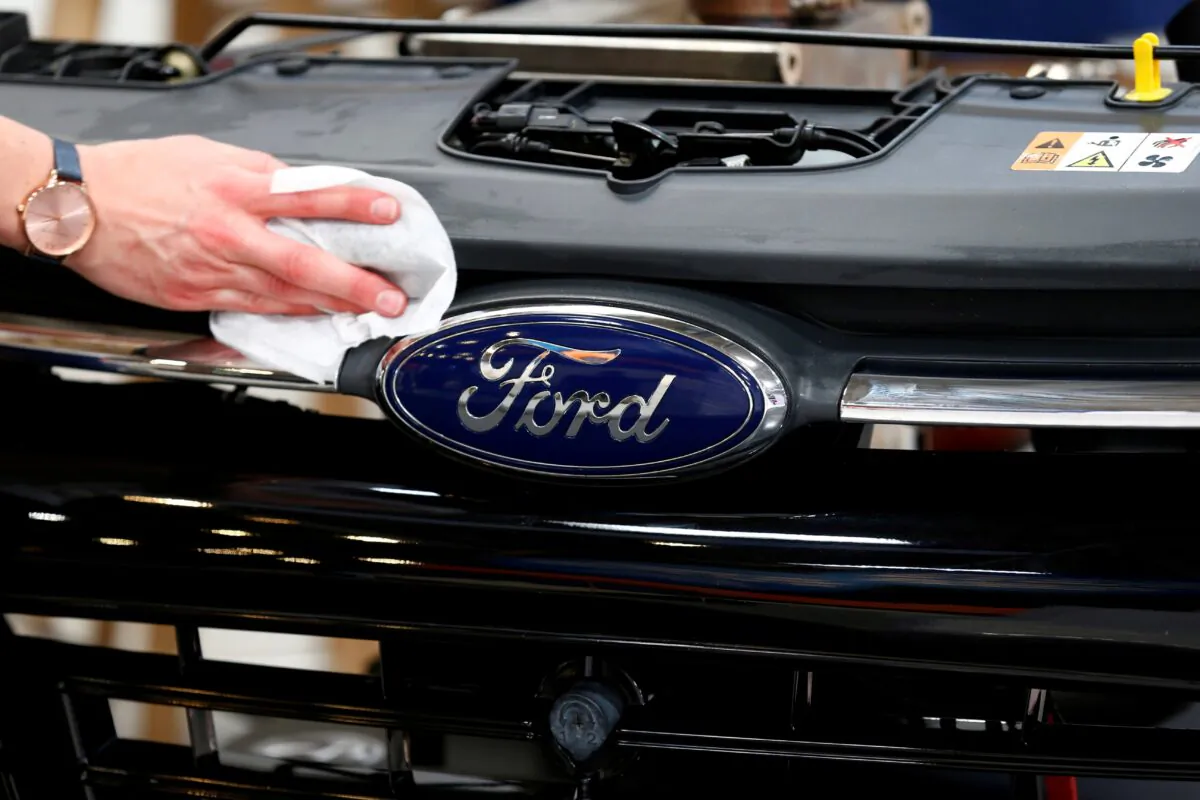 A worker cleans a part of the front of a Ford ahead of the Munich Motor Show IAA Mobility 2021 in Munich on Sept. 6, 2021. (Michaela Rehle/Reuters)