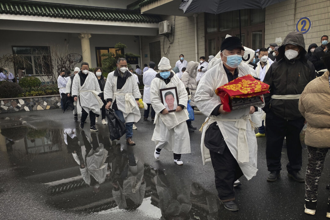 A mourner carries the cremated remains of a loved one as he and others wear traditional white funeral clothing, during a funeral in Shanghai. (Kevin Frayer/Getty Images)