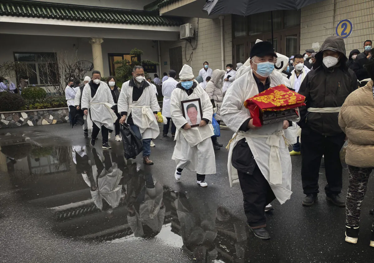 A mourner carries the cremated remains of a loved one as he and others wear traditional white funeral clothing, during a funeral in Shanghai. (Kevin Frayer/Getty Images)