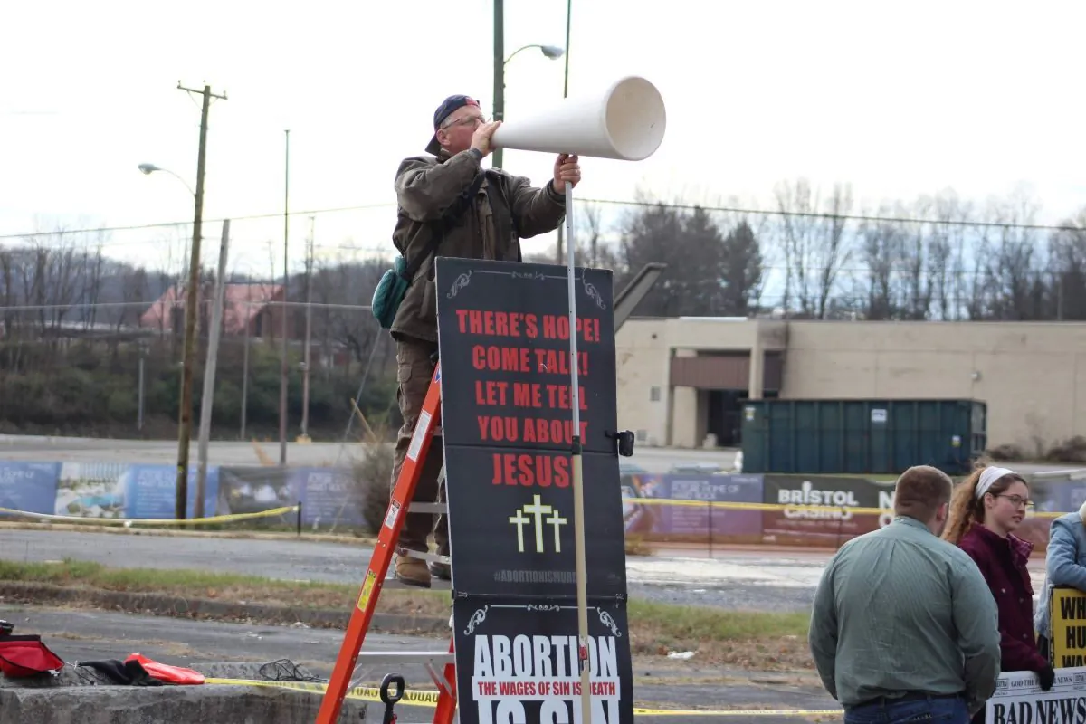 Coleman Boyd stands on a ladder near an abortion facility in Bristol, Va., in December 2022. (Sammi Cooper, Courtesy Coleman Boyd)