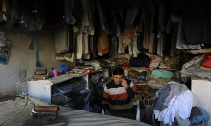 A laundryman uses a cell phone as he sits at his shop during country-wide power breakdown in Peshawar, Pakistan, on Jan. 23, 2023. (Fayaz Aziz/Reuters)