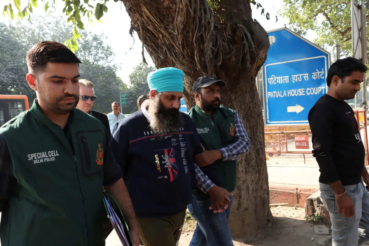Policemen escort Rajwinder Singh, 38, after he was arrested in New Delhi on Nov. 25, 2022. (Dinesh Joshi/AP Photo)