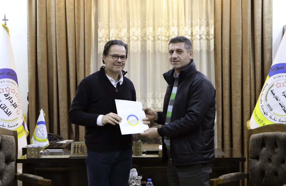 Stéphane Romatet, head of the crisis management and support center in the French Foreign Ministry (L), poses for a photo with Robel Baho, Deputy Head of the External Relations Department of the Autonomous Administration of North and East Syria, after signing a document of surrender for women and children of ISIS terrorists, at the department's headquarters in the city of Qamishli, Syria, on Jan. 23, 2023. (Autonomous Administration of North and East Syria via AP)