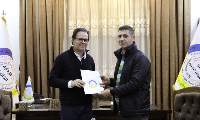 Stéphane Romatet, head of the crisis management and support center in the French Foreign Ministry (L), poses for a photo with Robel Baho, Deputy Head of the External Relations Department of the Autonomous Administration of North and East Syria, after signing a document of surrender for women and children of ISIS terrorists, at the department's headquarters in the city of Qamishli, Syria, on Jan. 23, 2023. (Autonomous Administration of North and East Syria via AP)