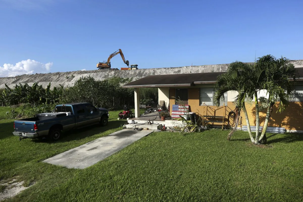 Rehabilitation work takes place on top of the Herbert Hoover Dike surrounding Lake Okeechobee, just a few feet from a home in Pahokee, Fla., on Nov. 1, 2019. (Robert F. Bukaty/AP Photo)