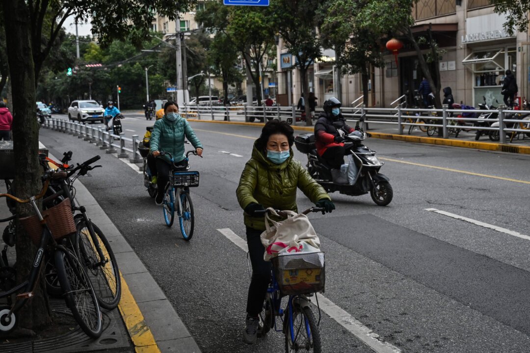 People ride bicycle on a street in the Jing'an district in Shanghai on Dec. 7, 2022. (Hector Retamal/AFP via Getty Images)