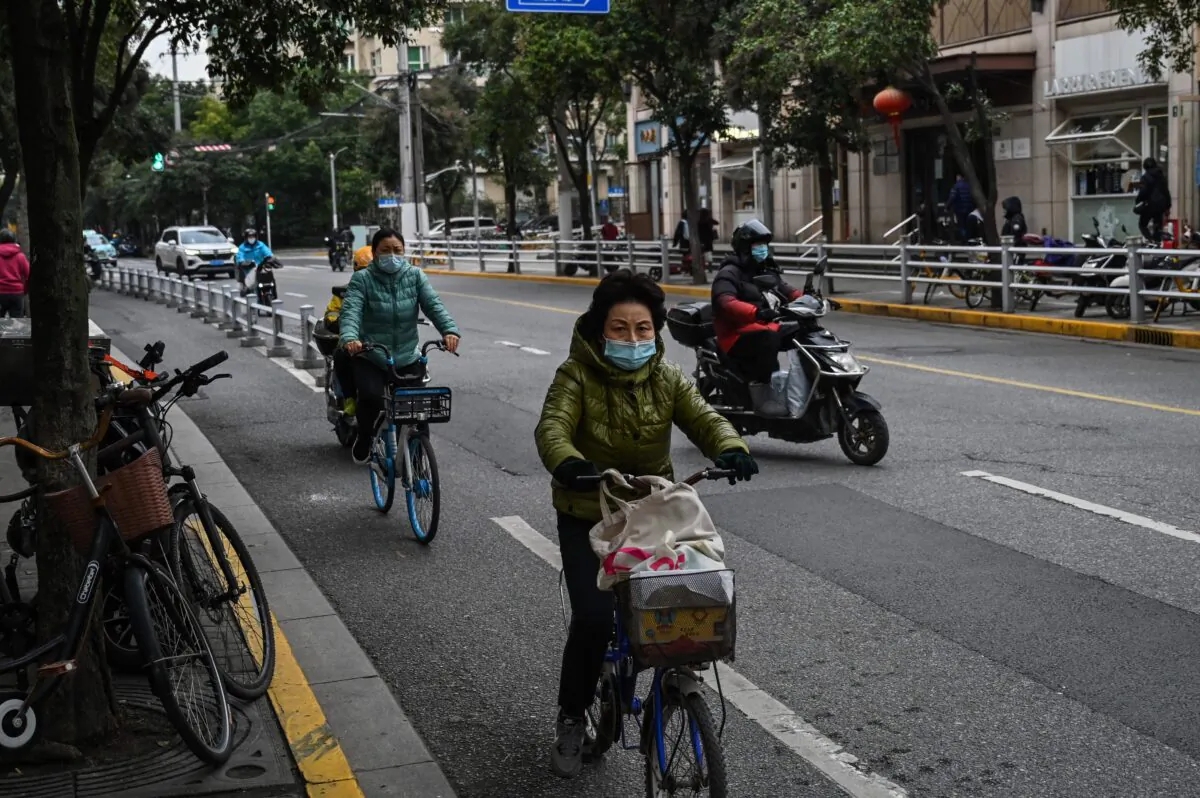 People ride bicycle on a street in the Jing'an district in Shanghai on Dec. 7, 2022. (Hector Retamal/AFP via Getty Images)