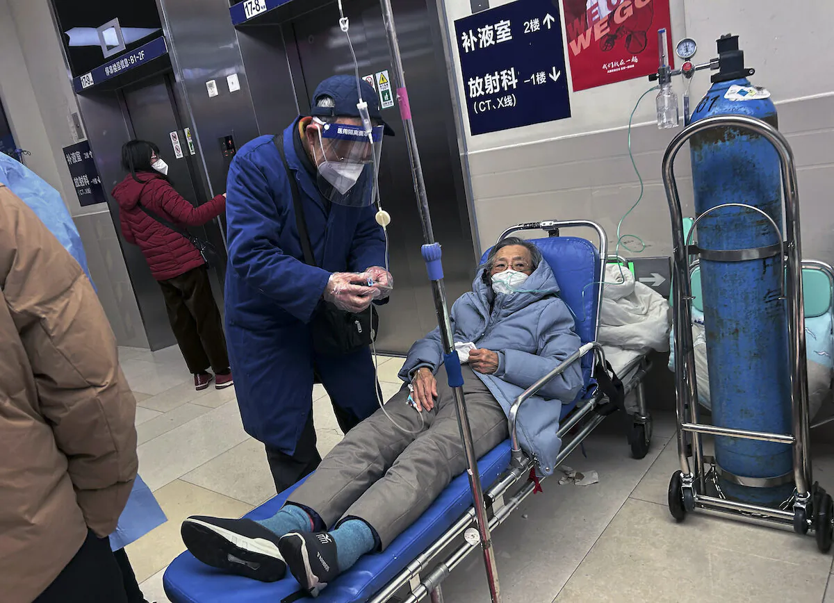 A man wears a face shield as he assists a loved one on a stretcher in the hallway of a busy hospital on Jan. 14, 2023, in Shanghai, China. (Kevin Frayer/Getty Images)