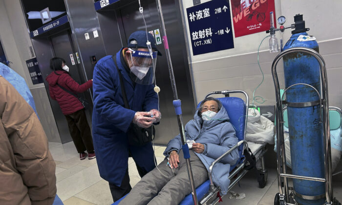 A man wears a face shield as he assists a loved one on a stretcher in the hallway of a busy hospital on Jan. 14, 2023, in Shanghai, China. (Kevin Frayer/Getty Images)