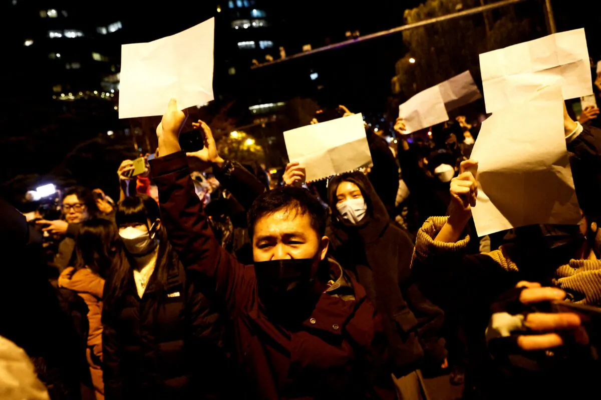 People gather for a vigil and hold white sheets of paper in protest of coronavirus disease (COVID-19) restrictions, as they commemorate the victims of a fire in Urumqi, as outbreaks of the coronavirus disease continue in Beijing, on Nov. 27, 2022. (Thomas Peter/Reuters)
