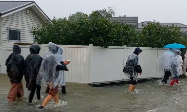 People walk on a flooded street after Elton John’s concert was canceled due to bad weather, in Auckland