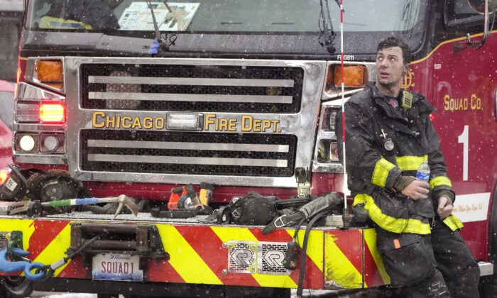 Chicago Firefighter Mose Demasi looks up at the Harper Square cooperative residential building after he and others fought a multi-floor fire at the high-rise in the Kenwood neighborhood of Chicago on Jan. 25, 2023. (Charles Rex Arbogast/AP Photo)