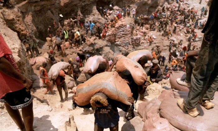 Artisanal miners carry sacks of ore at the Shabara artisanal cobalt mine near Kolwezi on Oct. 12, 2022. Demand for the metal is exploding due to its use in the rechargeable batteries that power mobile phones and electric cars. (Junior Kannah/AFP via Getty Images)