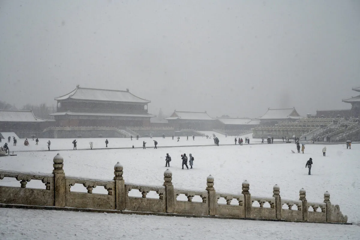 People visit the Forbidden City during a late spring snowfall in Beijing on March 18, 2022. (Kevin Frayer/Getty Images)