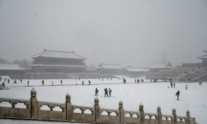 People visit the Forbidden City during a late spring snowfall in Beijing on March 18, 2022. (Kevin Frayer/Getty Images)