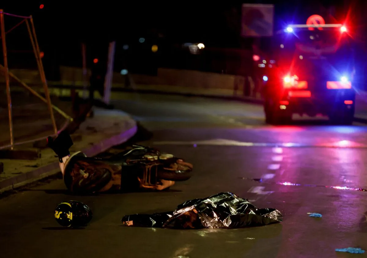 Israeli forces work next to a covered body at the scene of a shooting attack in Neve Yaacov which lies on land that Israel annexed to Jerusalem after the Six-Day War in 1967, on Jan. 27, 2023. (Ammar Awad/Reuters)