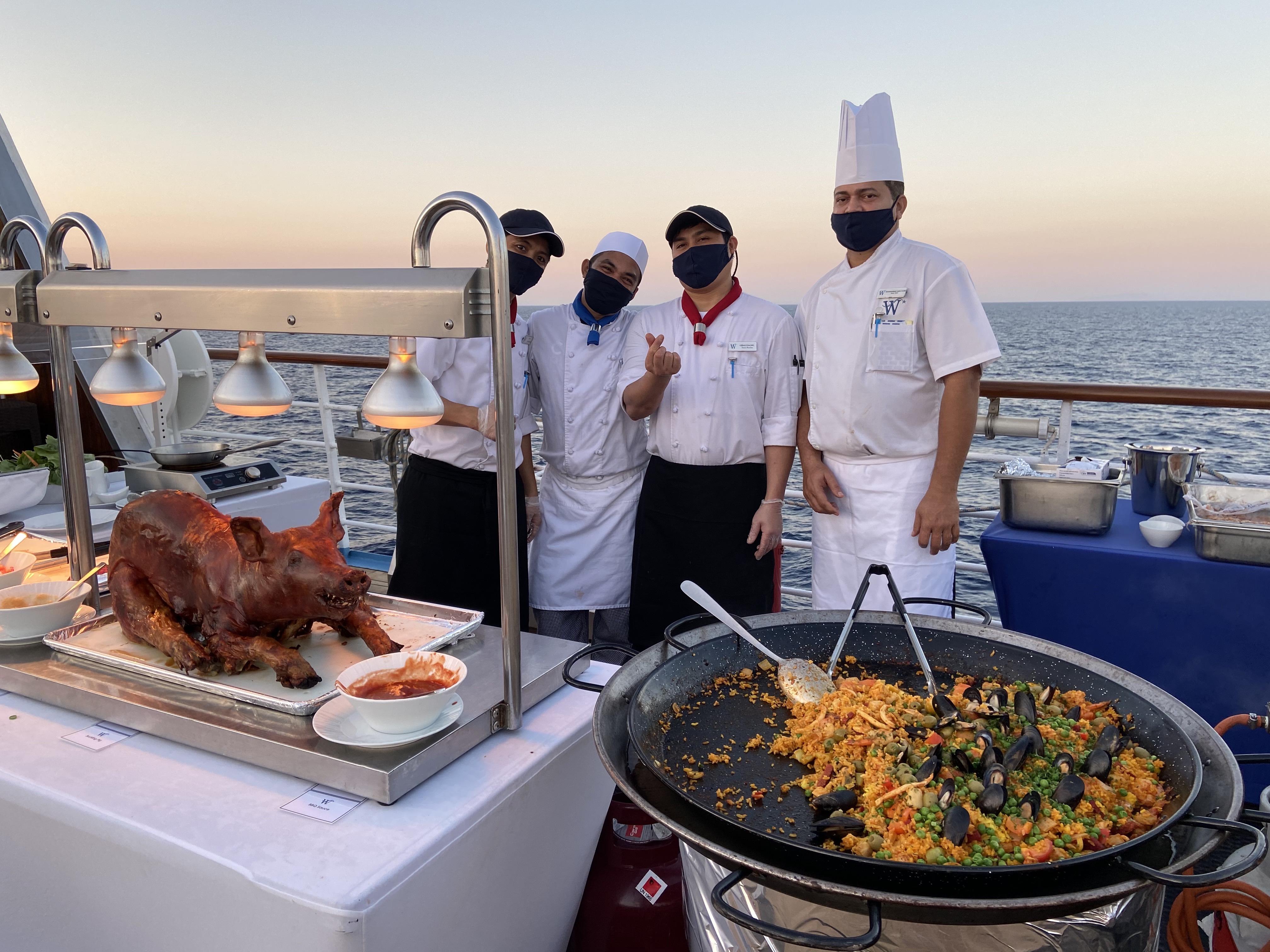 masked chefs on a cruise serving whole roasted pig