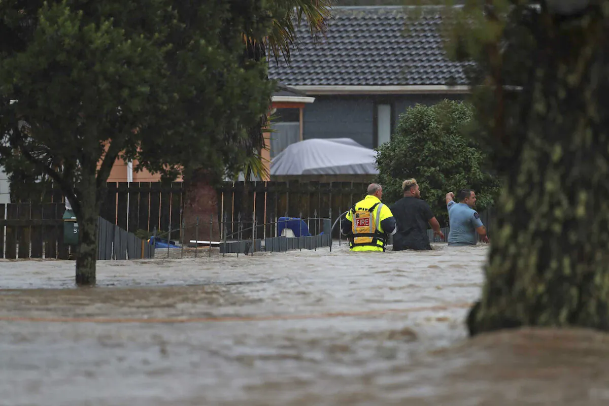 Emergency workers and a man wade through flood waters in Auckland, New Zealand, on Jan. 27, 2023. (Hayden Woodward/New Zealand Herald via AP)
