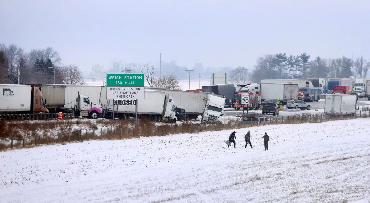 Individuals carry their belongings as they walk away as emergency crews respond to a multi-vehicle accident in Turtle, Wis., on Jan. 27, 2023. (Anthony Wahl/The Janesville Gazette via AP)