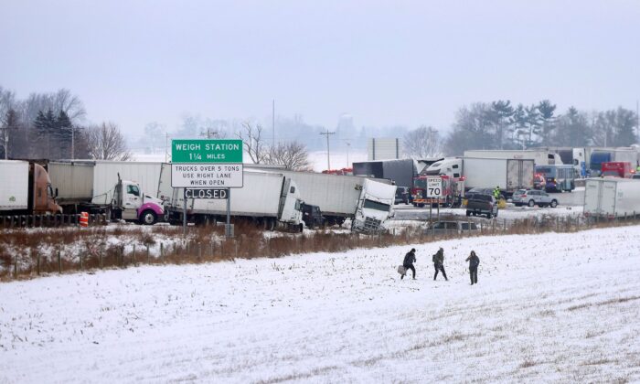 Individuals carry their belongings as they walk away as emergency crews respond to a multi-vehicle accident in Turtle, Wis., on Jan. 27, 2023. (Anthony Wahl/The Janesville Gazette via AP)