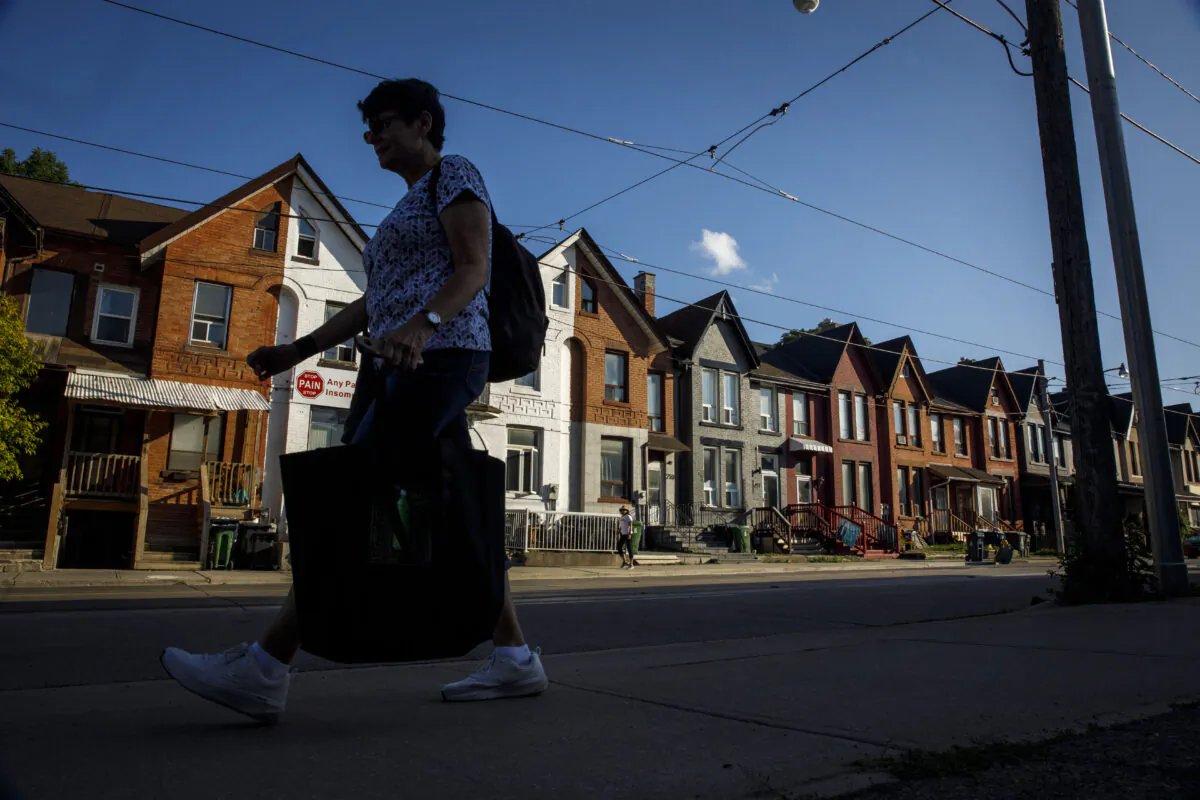 A person walks by a row of houses in Toronto on July 12, 2022. (Cole Burston/The Canadian Press)
