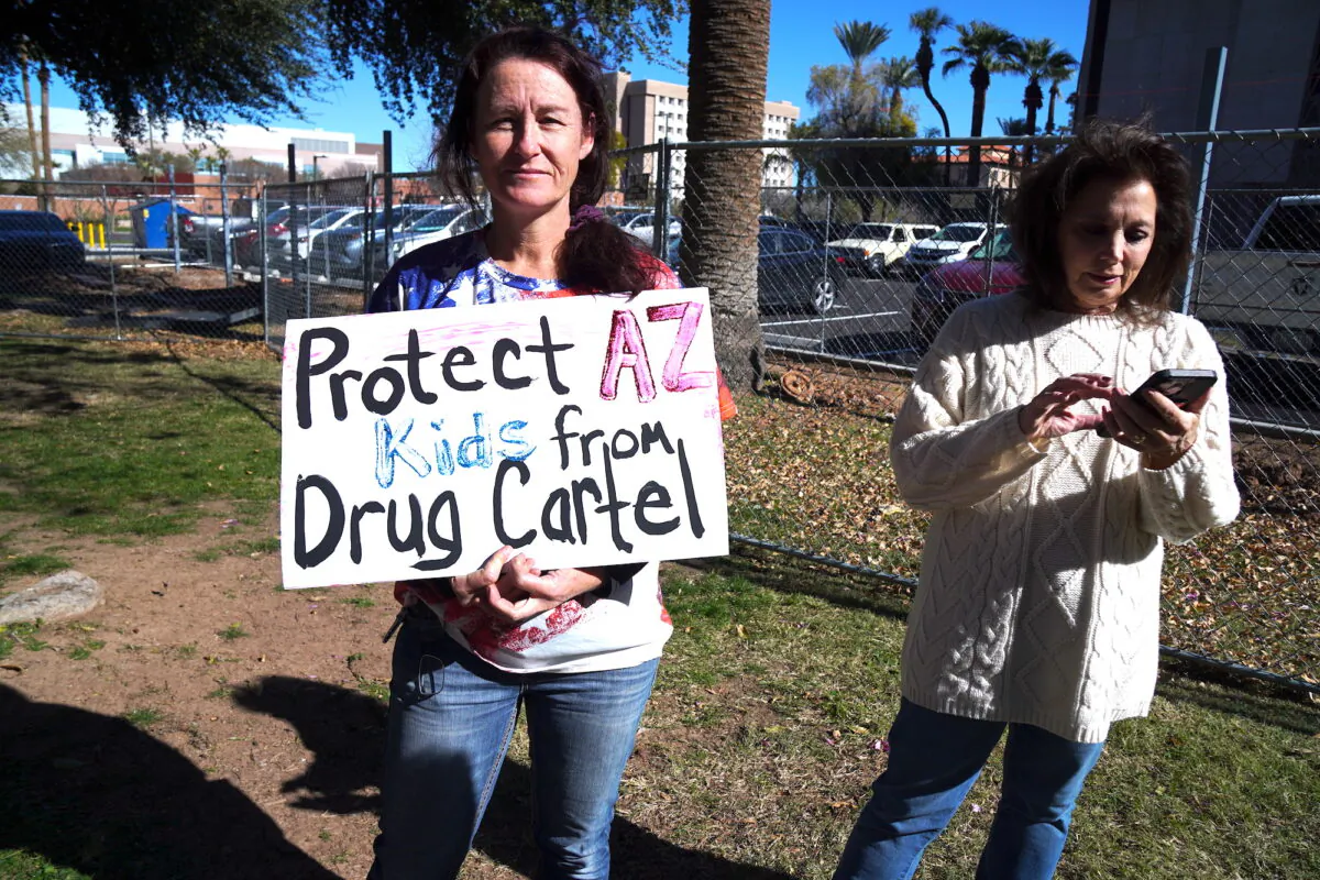 First responder and paramedic Carley Morgan holds a sign protesting Mexican drug cartels at a press conference on the border crisis in Phoenix on Jan. 26, 2023. (Allan Stein/The Epoch Times)
