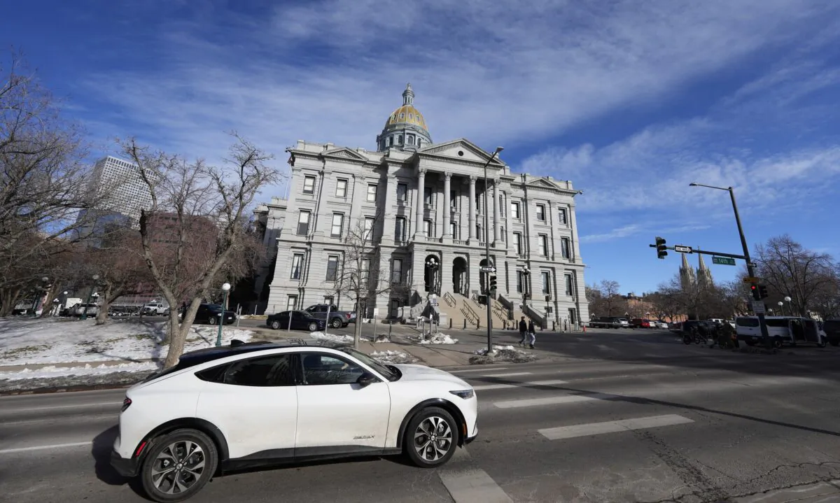 An 2022 Ford Mustang Mach E whips past the State Capitol as the legislative session opens in the House of Representatives in the Senate chambers in Denver on Jan. 9, 2023. (David Zalubowski/AP Photo)