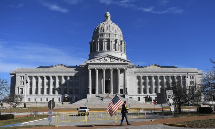 A man waves and American flag as he walks outside the Missouri State Capitol building in Jefferson City, Mo., on Jan. 20, 2021. (Michael B. Thomas/Getty Images)