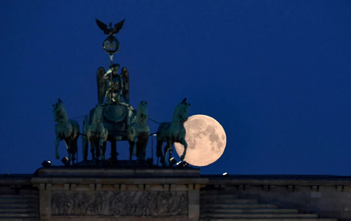 An almost full moon behind the quadriga of Brandenburg Gate in Berlin on April 7, 2020. (Annegret Hilse/Reuters)