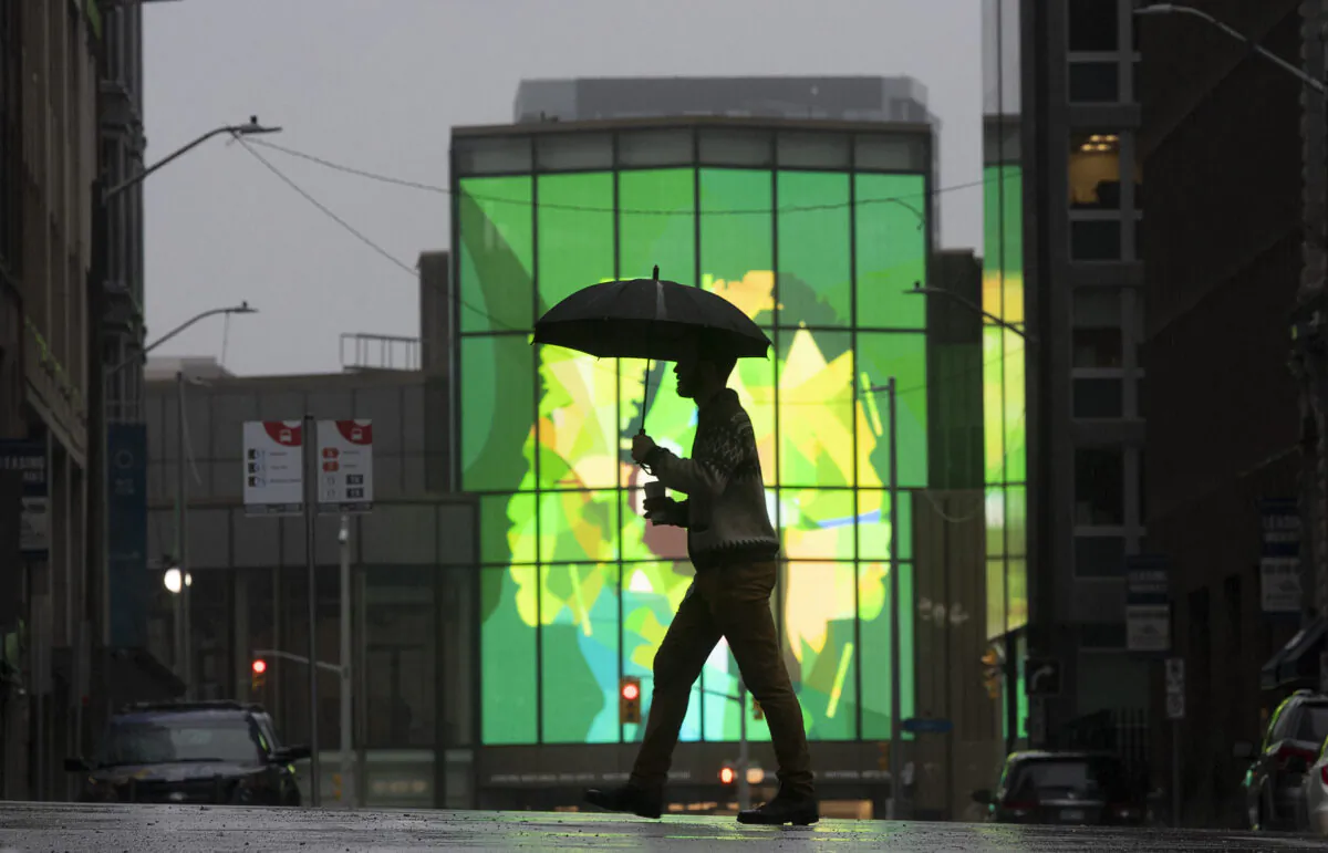 A man is silhouetted as he crosses the street near the National Arts centre in downtown Ottawa on March 26, 2021. (Adrian Wyld/The Canadian Press)