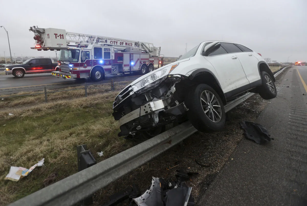 A vehicle rests on a barricade as the driver lost control and slid off Highway 6, in Waco, Texas on Jan. 31, 2023. (Jerry Larson/Waco Tribune-Herald via AP)