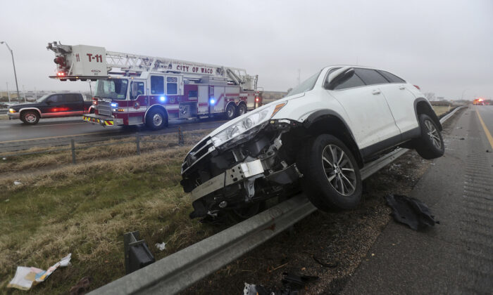 A vehicle rests on a barricade as the driver lost control and slid off Highway 6, in Waco, Texas on Jan. 31, 2023. (Jerry Larson/Waco Tribune-Herald via AP)