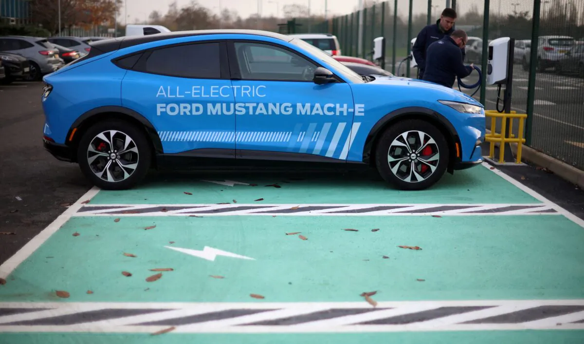 Workers plug in an electric Ford Mustang Mach-e electric vehicle during a press event at the Ford Halewood transmissions plant in Liverpool, Britain, on Dec. 1, 2022. (Phil Noble/Reuters)