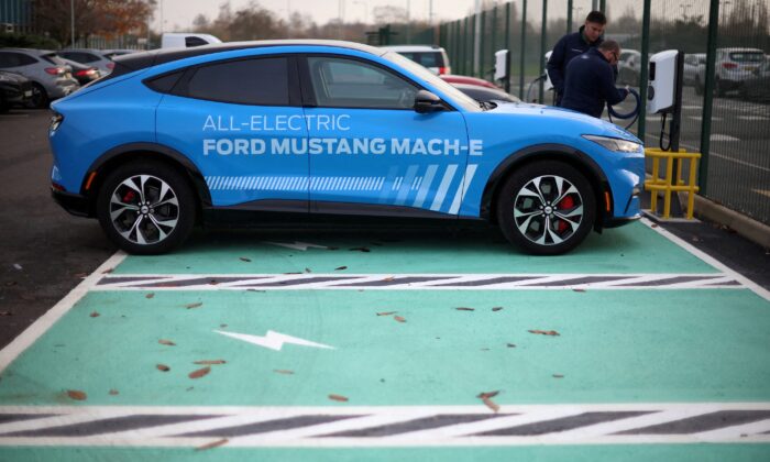 Workers plug in an electric Ford Mustang Mach-e electric vehicle during a press event at the Ford Halewood transmissions plant in Liverpool, Britain, on Dec. 1, 2022. (Phil Noble/Reuters)