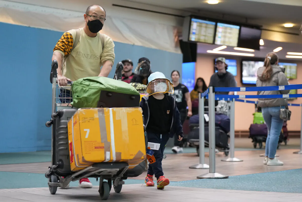 A man and young boy who arrived on a Cathay Pacific flight from Hong Kong walk together at Vancouver International Airport, in Richmond, B.C., on Jan. 4, 2023. (Darryl Dyck/The Canadian Press)