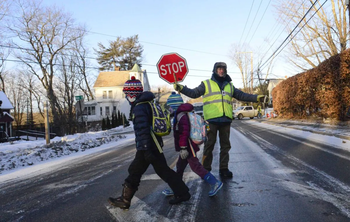 Bundled up, Tom Gilbert, a crossing guard for Windham Southeast Supervisory Union, helps students cross Western Avenue in Brattleboro, Vt., on Feb. 4, 2023, on their way to school. (Kristopher Radder/The Brattleboro Reformer via AP)
