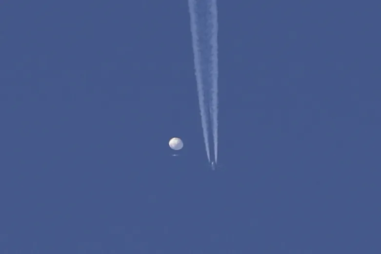 A large balloon drifts above the Kingstown, N.C. area, with an airplane and its contrail seen below it. (Brian Branch via AP)