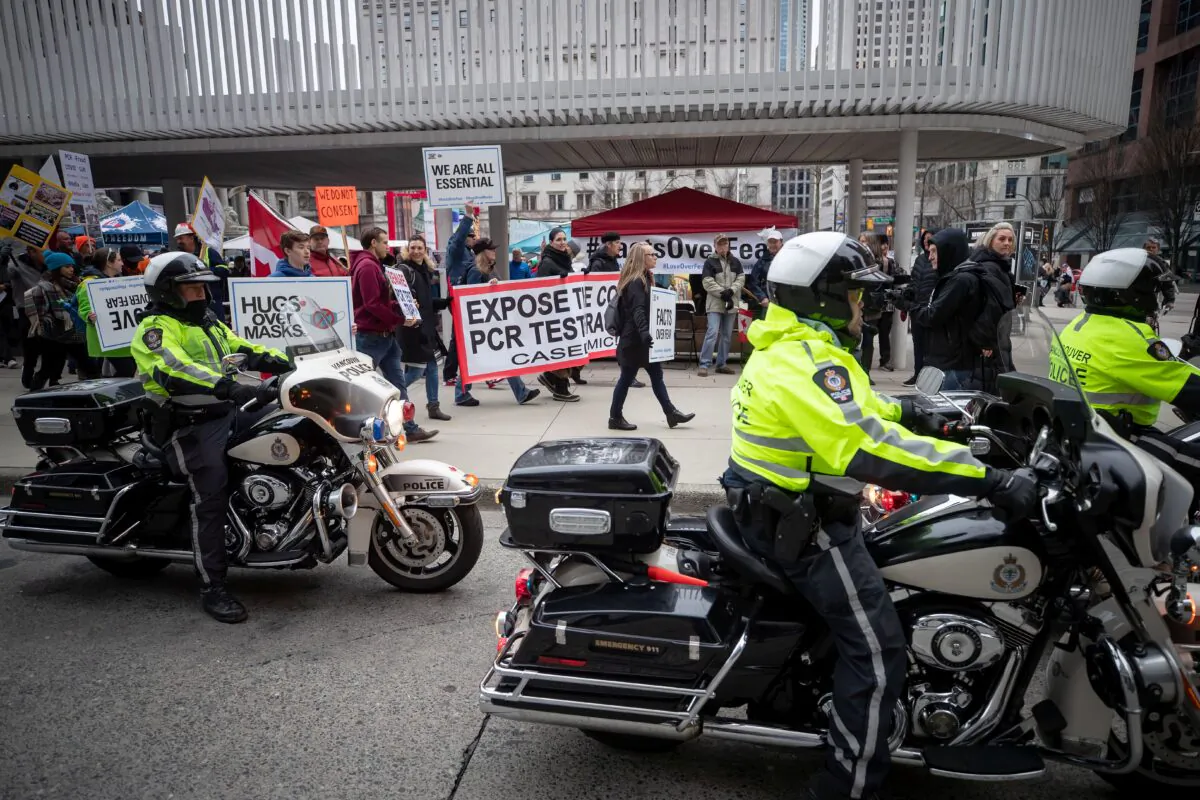 People opposed to COVID-19 restrictions are given a police escort as they march in Vancouver on Feb. 20, 2021. (The Canadian Press/Darryl Dyck)