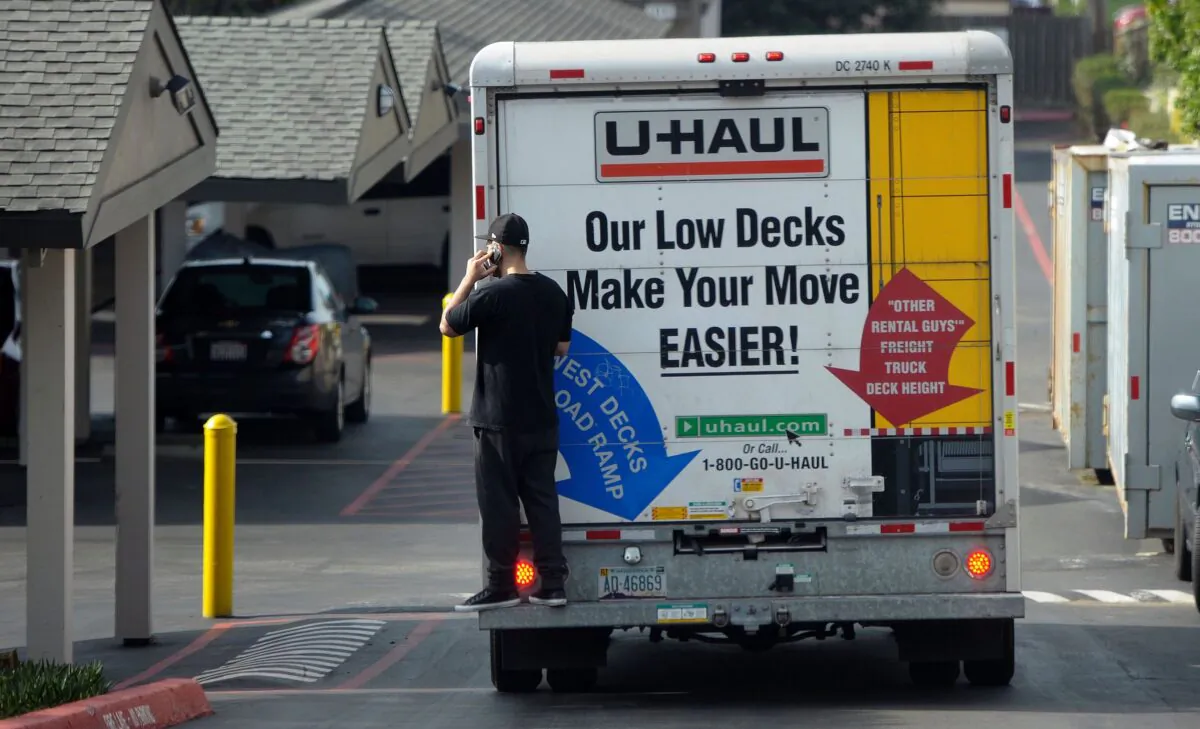 A man talks on his cell phone while riding on the back of a moving truck in Pacifica, Calif., on Jan. 26, 2016. (Josh Edelson/AFP via Getty Images)