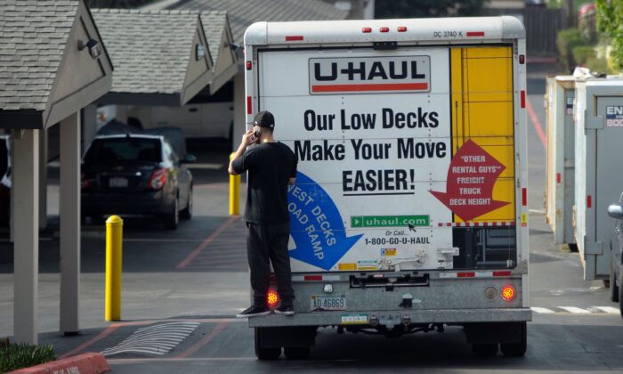 A man talks on his cell phone while riding on the back of a moving truck in Pacifica, Calif., on Jan. 26, 2016. (Josh Edelson/AFP via Getty Images)
