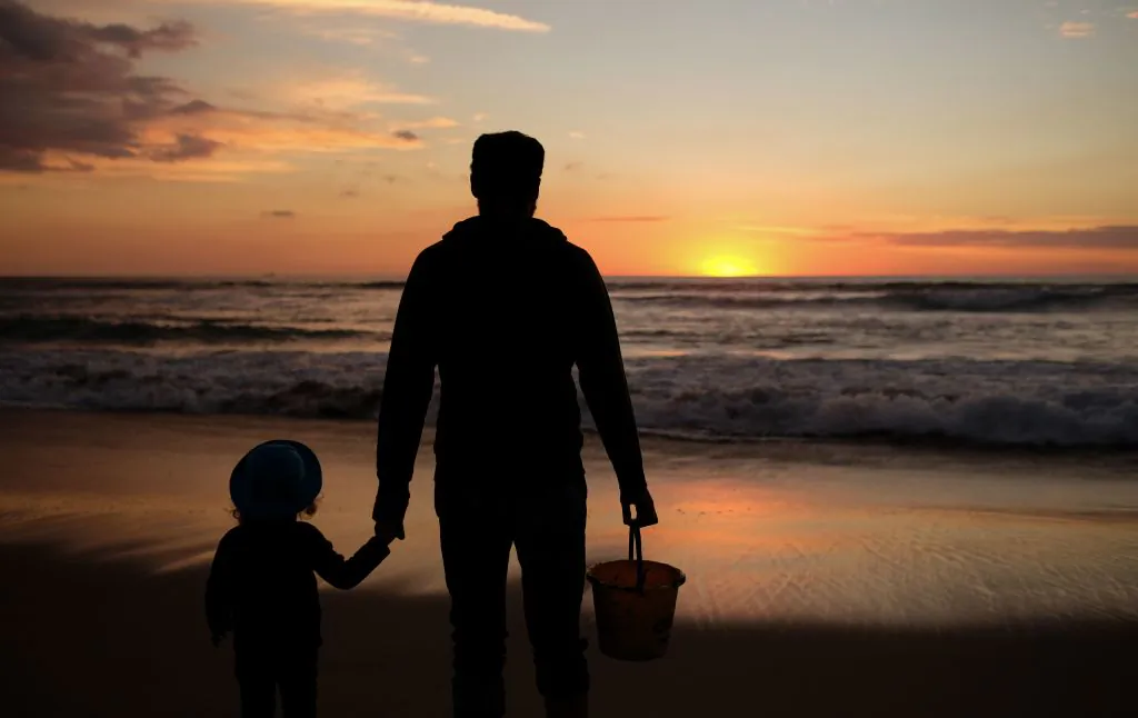 A dad and his daughter enjoy the last sunset of the year in Manhattan Beach, Calif., on Dec. 31, 2018. (Chris Delmas/AFP via Getty Images)